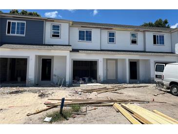 New townhomes under construction with garage and light gray and white siding and trim detail at 4252 Campsite Loop, Orlando, FL 32824