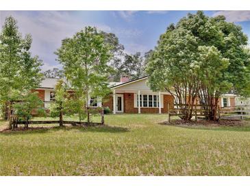 Charming brick home featuring a large front yard with mature trees and a rustic wooden fence at 4802 Anton Ave, Apopka, FL 32712