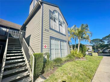 Two-story condo with beige siding, large windows, lush landscaping, and metal stairway on a clear, sunny day at 936 Birmingham Ct # 200, Lake Mary, FL 32746