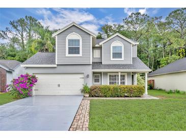 Charming two-story home featuring a manicured lawn, gray siding, and an attached two-car garage at 1576 Crosswind Cir, Orlando, FL 32825