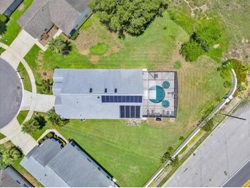 A beautiful aerial view of the home, showcasing the screened pool, solar panels, and spacious lawn at 2627 Autumn Creek Cir, Kissimmee, FL 34747