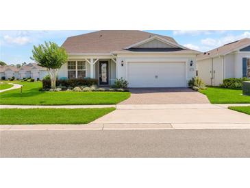 Charming single-Gathering home showcasing a lush front lawn, mature tree, and brick-paved driveway at 2793 Nature View Rd, St Cloud, FL 34771