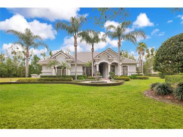 Stunning home featuring lush lawn, mature palms, circular driveway, and fountain at 5241 Vista Club Run, Sanford, FL 32771