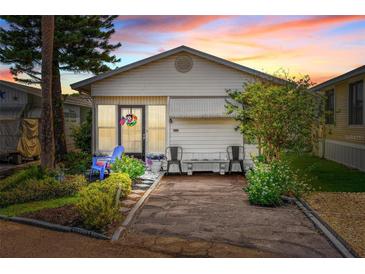 Charming single-story home featuring a well-manicured front yard, vibrant plants, and covered porch seating at 9000 Us Highway 192 # 115, Clermont, FL 34714
