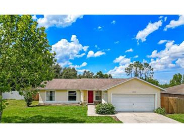 Charming single-story home with a well-manicured lawn, bright red front door and attached garage at 10739 Lake Ralph Dr, Clermont, FL 34711