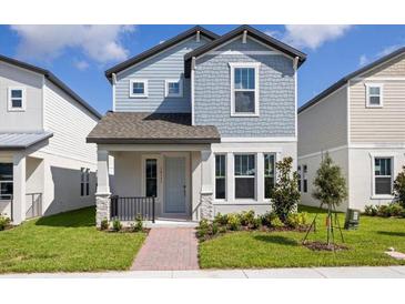 Charming two-story home boasts a beautiful blue exterior, well-manicured lawn, and welcoming front porch at 14111 Frasier St, Winter Garden, FL 34787