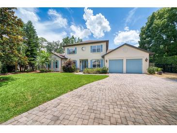 Inviting two-story home featuring a well-manicured lawn, blue shutters and a paver driveway leading to a two-car garage at 1420 Palmer Ave, Winter Park, FL 32789