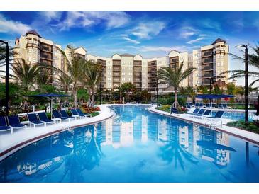 Stunning pool area with lounge chairs and umbrellas surrounded by tropical landscaping and the building's reflection at 14501 Grove Resort Ave # 2451, Winter Garden, FL 34787