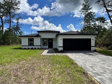 Charming single-story home with a black two-car garage and beautifully paved driveway at 16463 Sw 55Th Court Rd, Ocala, FL 34473