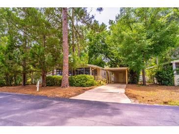 Charming single-story home with a covered carport nestled among lush green trees and landscaping at 203 N Forest Blvd, Lake Mary, FL 32746
