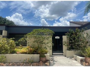 Charming home's entrance with a gated courtyard and lush landscaping under a partly cloudy sky at 2426 Windward Way, Winter Park, FL 32792