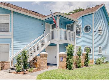 Charming blue condo with white staircase, American flag, and well-maintained landscaping at 2729 N Poinciana Blvd # 125, Kissimmee, FL 34746