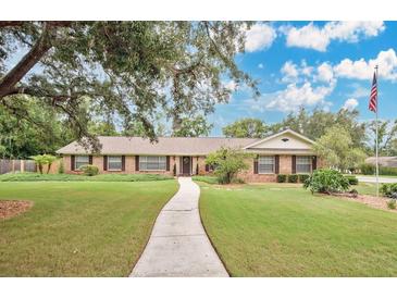 Charming single-story home features a well-manicured lawn and a welcoming front entrance with an American flag at 603 S Sweetwater Blvd, Longwood, FL 32779