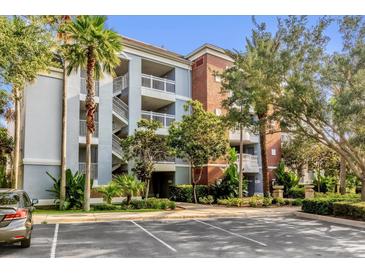 Exterior view of a three-story condominium building with manicured landscaping and ample parking at 1100 Sunset View Cir # 204, Reunion, FL 34747