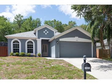 Charming gray home featuring arched windows, a two-car garage, and manicured landscaping at 1322 Reagans Reserve Blvd, Apopka, FL 32712