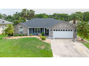 Charming home with a well-manicured lawn, stone accents, and an attached two-car garage at 1639 Yellow Brick Rd, Astor, FL 32102