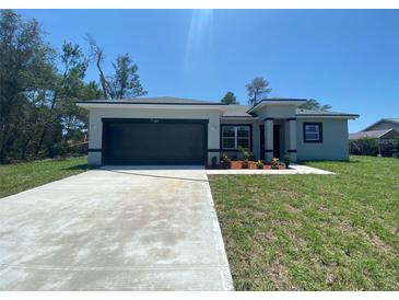 Charming single-story home with a dark grey garage door, fresh landscaping, and a well-manicured lawn at 182 Marion Oaks Mnr, Ocala, FL 34473