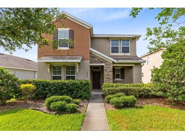 Inviting two-story home with manicured landscaping, stone accents, and a cozy front porch at 1978 J Lawson Blvd, Orlando, FL 32824