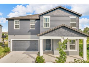Charming two-story home with blue siding, a gray garage door, and a covered front porch at 2210 Derwent Dr, Davenport, FL 33896