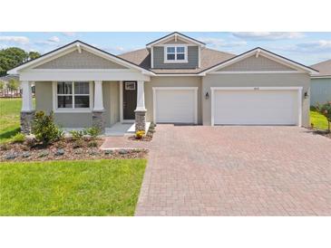 Charming single-story home with a two-car garage, brick-paved driveway, well-manicured lawn, and attractive landscaping at 2639 Ginseng Ivy St, Apopka, FL 32703