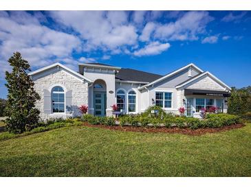 Single-story home featuring stone accents, arched entryway, landscaped front yard, and visible 'Sales Center' sign at 3126 Wolf Lake Ave, Apopka, FL 32712
