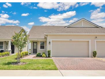 Inviting single story home featuring well-manicured lawn, paver driveway, and attached two-car garage at 3280 Canna Lily Pl, Clermont, FL 34711