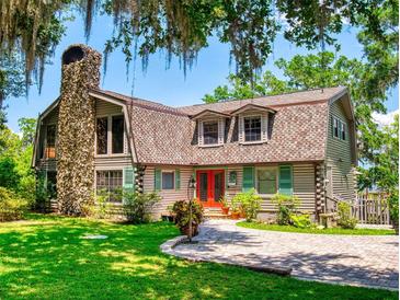 Charming exterior of home with a stone chimney, wood siding, and a well-manicured lawn at 3443 S Mellonville Ave, Sanford, FL 32773