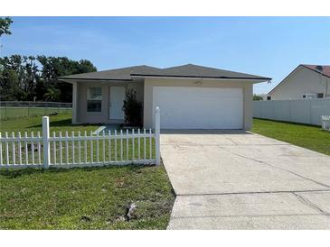 Charming single-story home featuring a white picket fence, green lawn, and attached two-car garage at 909 San Paulo Way, Kissimmee, FL 34758