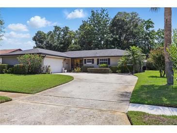 Charming single-story home featuring a well-manicured lawn and a spacious driveway leading to an attached two-car garage at 1017 Manchester Cir, Winter Park, FL 32792