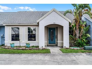 Inviting home exterior featuring a stucco facade, blue door, and lush landscaping at 116 Candlewick Ct, Sanford, FL 32771