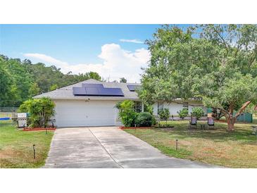 Charming single-story home with a well-manicured lawn, mature tree, solar panels, and a two-car garage at 2771 Ne 66Th St, Ocala, FL 34479