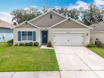 Charming single-story home boasts a well-manicured lawn, lovely landscaping, and a two-car garage at 29746 Anahid Dr, Leesburg, FL 34748
