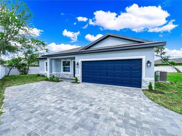 Beautiful home exterior features a blue garage door, paver driveway, manicured lawn, and decorative stone accents at 331 Erie Ct, Kissimmee, FL 34759