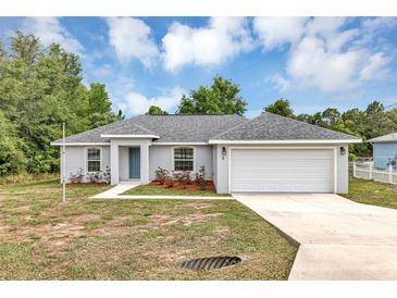 Charming single-story home with a well-maintained lawn, blue door, and attached two-car garage at 8 Water Trce, Ocala, FL 34472