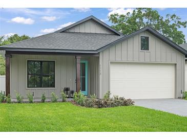 Charming single-story home featuring board and batten siding, a blue door and an attached garage at 1113 Naples Dr, Orlando, FL 32804