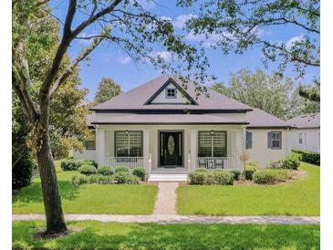 Charming single-story home featuring a well-manicured lawn, inviting front porch, and sophisticated black door at 11721 Camden Park Dr, Windermere, FL 34786