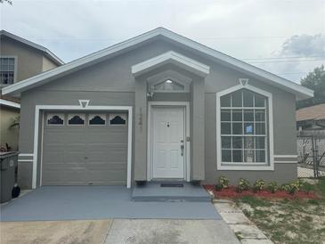 Charming single-story home with a gray exterior, updated landscaping, and an attached one-car garage at 1241 Cleveland Ave, Apopka, FL 32703
