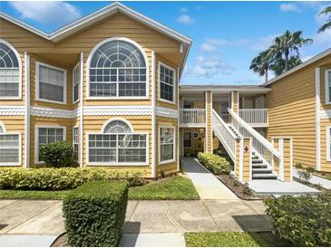 Charming yellow condominium with large windows, white trim, and manicured landscaping at 3142 Britannia Blvd # C, Kissimmee, FL 34747
