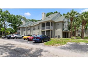 This is an exterior view of the condo building, showcasing its architecture, surrounding greenery, and parking area for residents at 6052 Westgate Dr # 204, Orlando, FL 32835