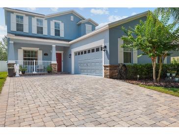 Beautiful two-story home with a charming porch and a brick driveway leading to the attached garage at 6333 Schoolhouse Pond Rd, Winter Garden, FL 34787
