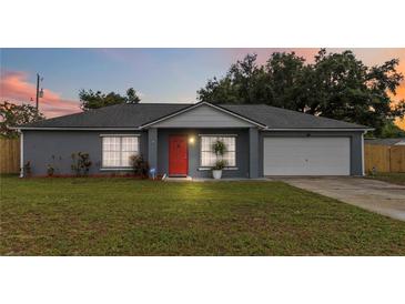 Charming single-story home featuring a well-maintained lawn, gray paint, and a red front door at 8 Lake Jackson Dr, Mascotte, FL 34753