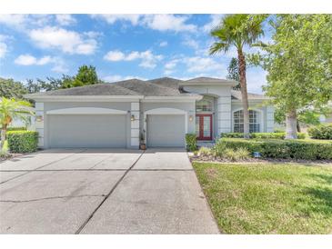 Beautiful single-story home with a well-manicured lawn, three-car garage, and a charming red front door at 10417 Oakview Pointe Ter, Gotha, FL 34734