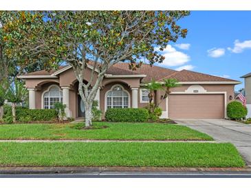 Charming single-story home featuring a well-manicured lawn and inviting curb appeal with lush landscaping at 12207 Shadowbrook Ln, Orlando, FL 32828