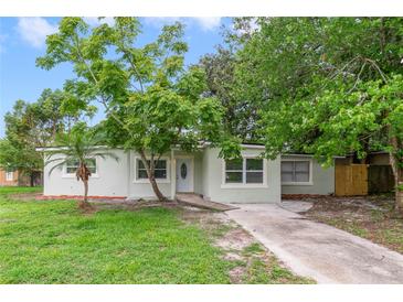 Charming one-story home with light-green exterior, mature trees, and a well-maintained front yard at 147 Country Club Dr, Sanford, FL 32771