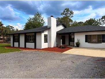 Charming single-story home featuring a white exterior, black trim, and well-manicured landscaping at 2630 S Tanner Rd, Orlando, FL 32820
