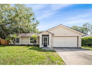 Charming single-story home featuring an attached two car garage and mature trees in the front yard at 3304 Vancouver Ave, Deltona, FL 32738