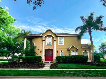 Charming two-story home with a well-manicured lawn, mature trees, and a red front door at 357 Fairway Pointe Cir, Orlando, FL 32828