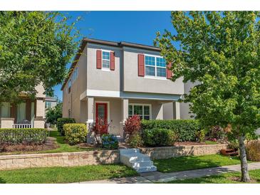 Charming two-story home with a red door, gray exterior paint and well-manicured landscaping at 9348 Meadow Hunt Way, Winter Garden, FL 34787