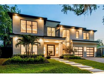 Stunning modern home with lush landscaping, illuminated walkway, and sleek, black-trimmed windows at 1211 Munster St, Orlando, FL 32803