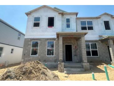 New construction home with visible framework, windows, and a concrete block base awaits its finishing touches at 15370 Burgtheater Dr, Winter Garden, FL 34787